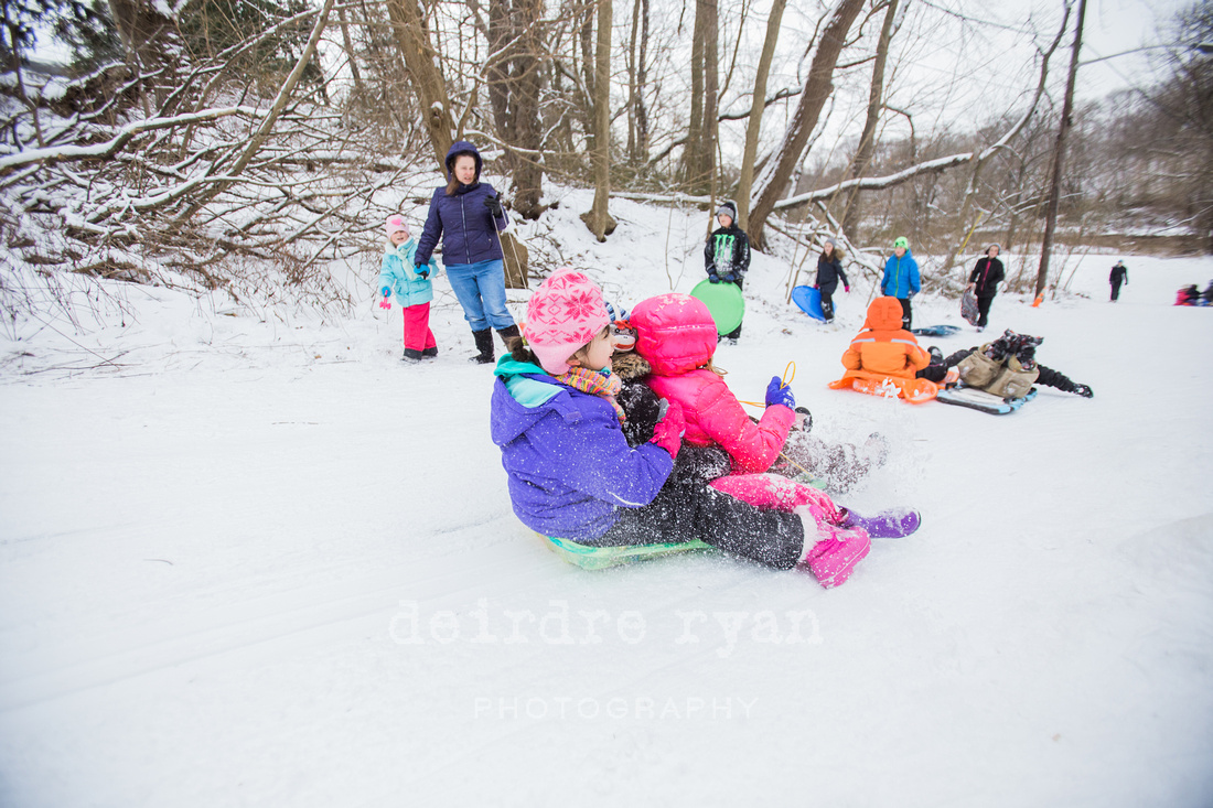 Children sledding down a hill on a snow day from school. Photo by Deirdre Ryan Photography